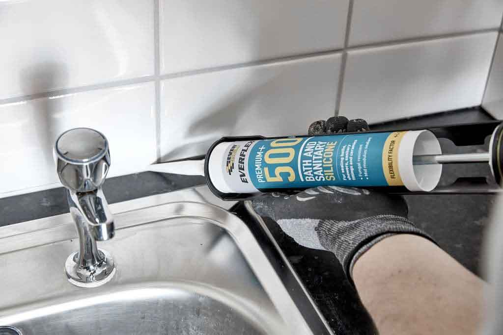 image of a man applying silicone sealant to the Bath